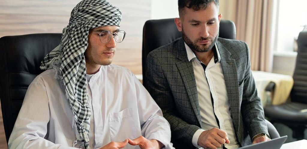 Image showing two men discussing work activity, one wearing a tradtional arabic Thawb