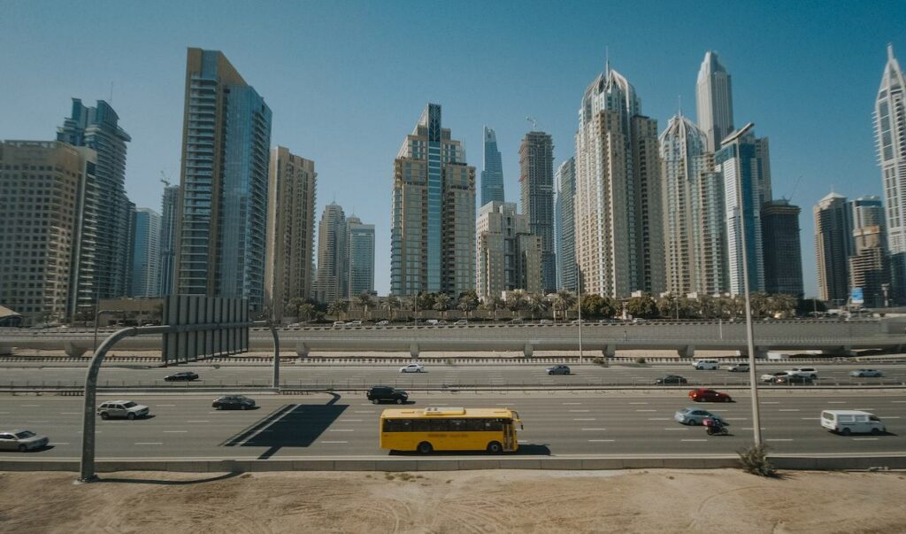 Image showing a busy highway with a yellow bus and Dubai's skyline in the near distance