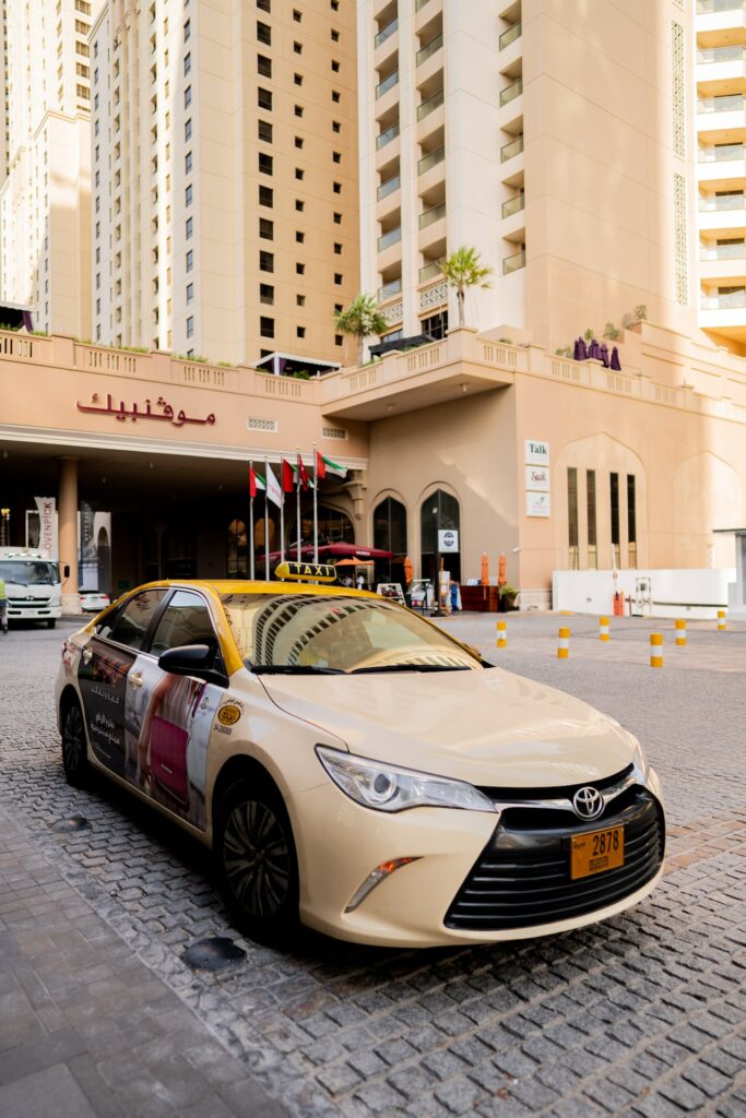 Image showing a yellow Dubai taxi waiting outside a hotel building